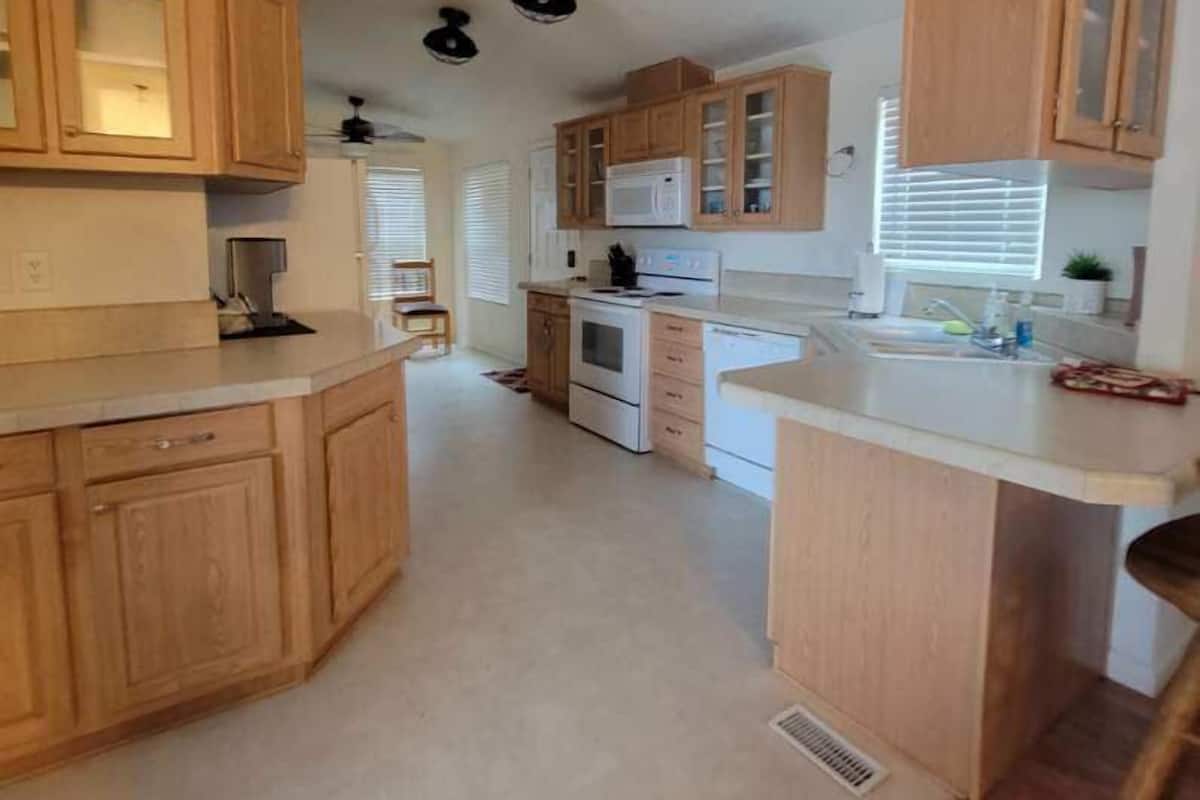 A modern kitchen with wooden cabinets, a central island, and a microwave.