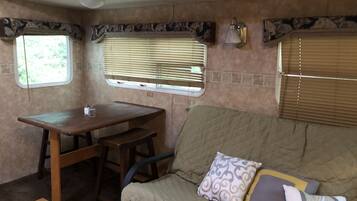 A cozy RV interior with a wooden table, bench, and a cushioned sofa with patterned pillows.
