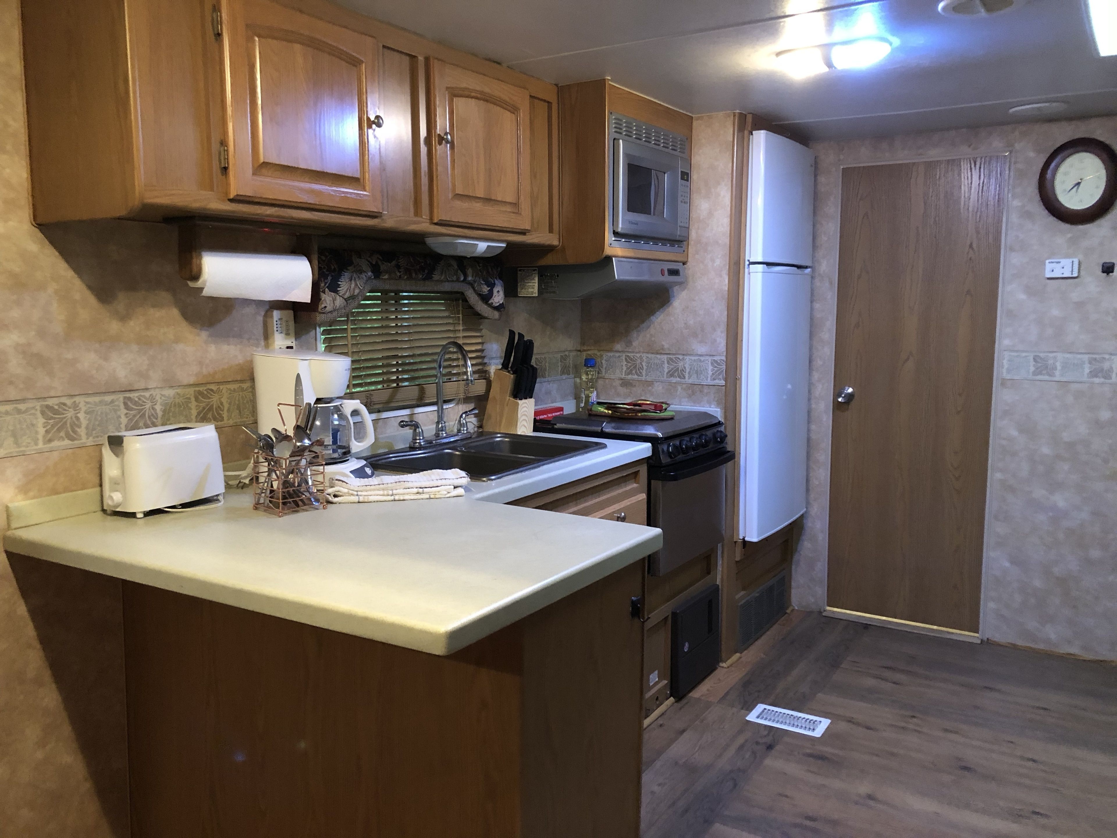 Una cocina compacta con armarios de madera, un microondas, una estufa y un refrigerador.