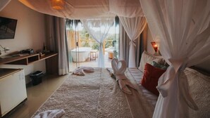 A bedroom with a large bed, a desk, and a view of the outdoors.