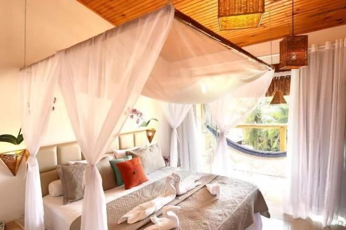 Un dormitorio con techo de madera, una cama con dosel y vistas al exterior.