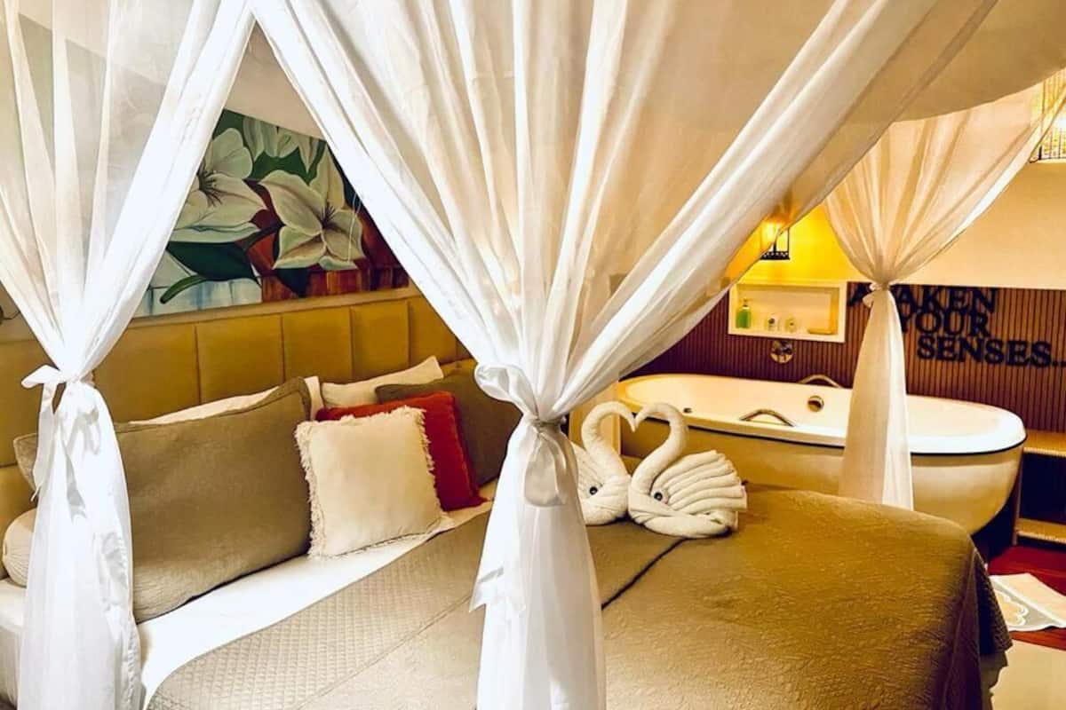 Una habitación de hotel con una cama, una bañera y un cuadro en la pared.