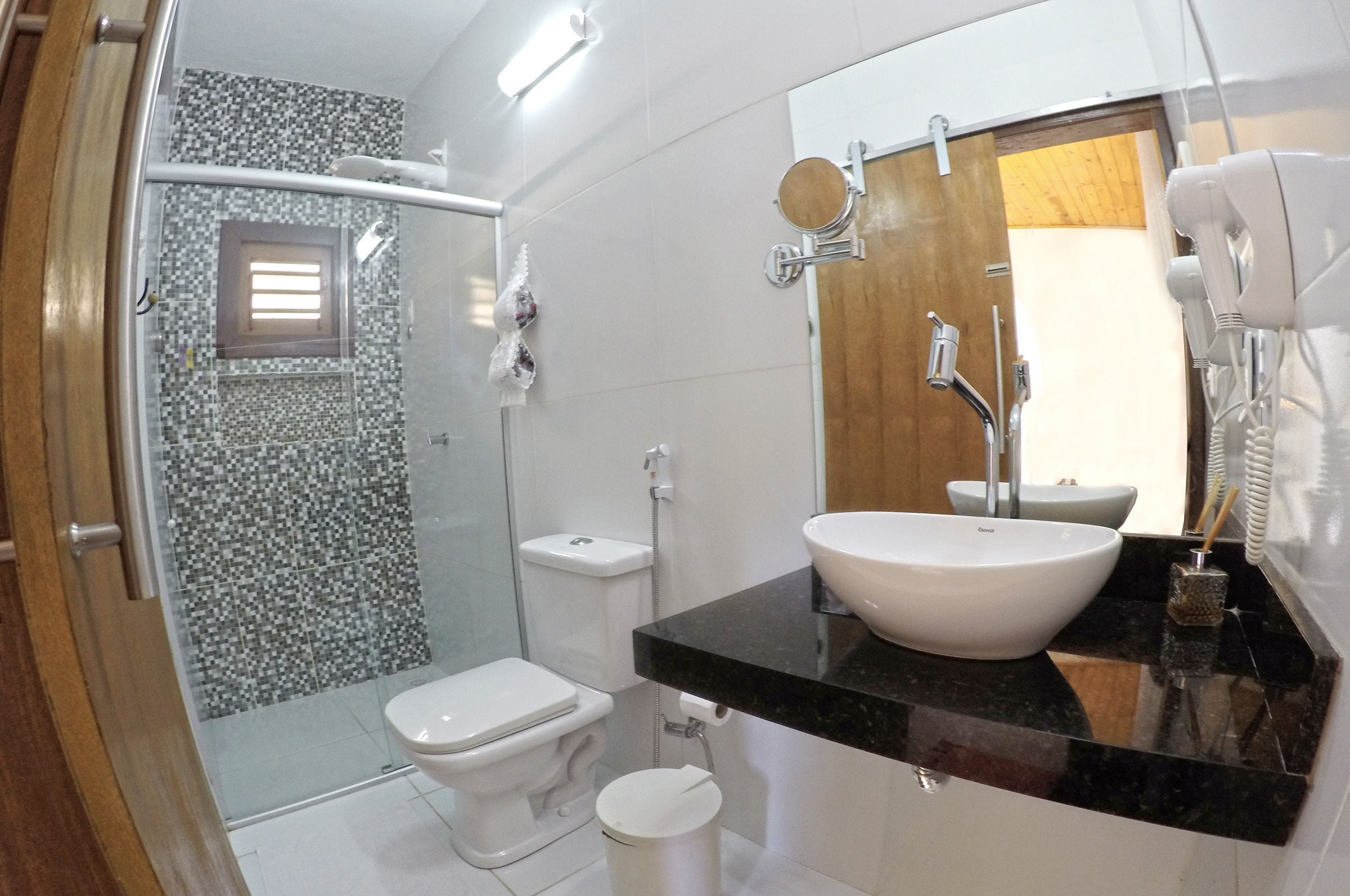A bathroom with a glass shower enclosure, a toilet, a sink with a mirror, and a towel rack.