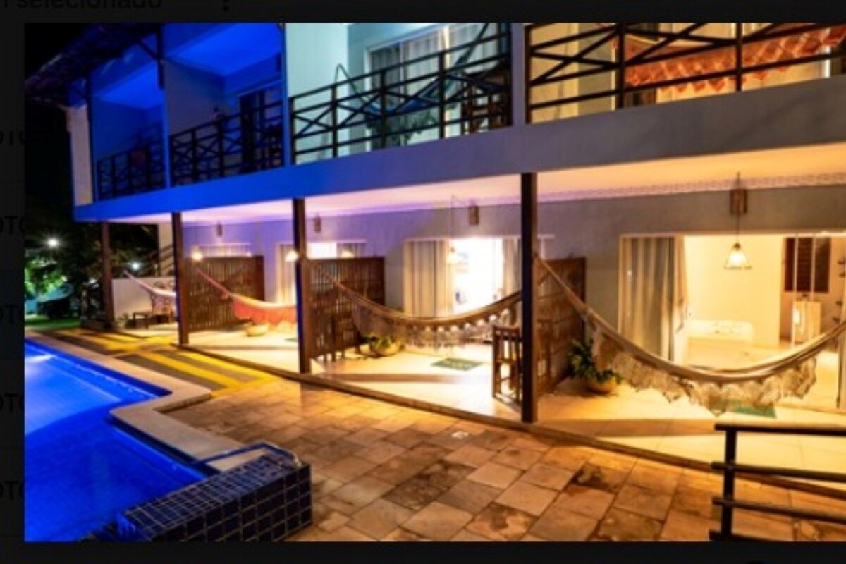 A two-story building with a pool, outdoor seating, and a hammock.