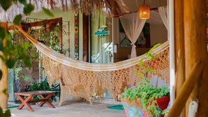 A hammock, a wooden bench, and potted plants in a tropical setting.