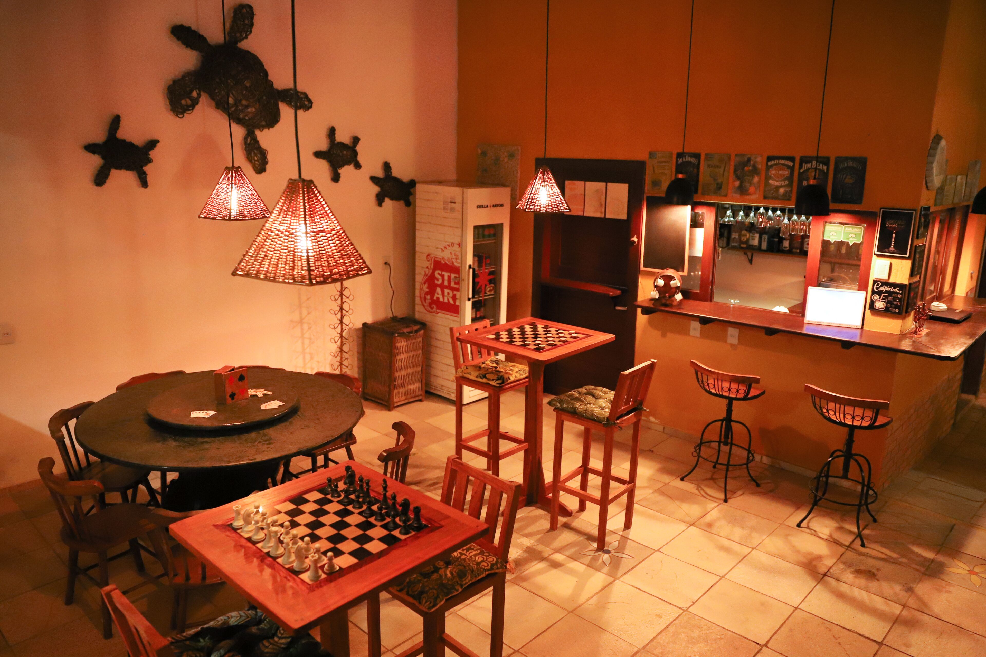 Eine gemütliche Bar mit Schachbrett, Holzstühlen und Pendelleuchten.