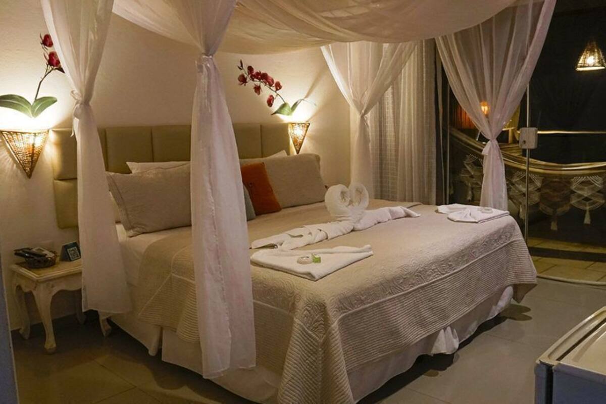 Un dormitorio con cama con dosel, lámparas de noche y vistas al exterior.