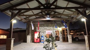 A building with a covered entrance, stone walls, and flags. - Ranch House Inn and Suites (Temple)