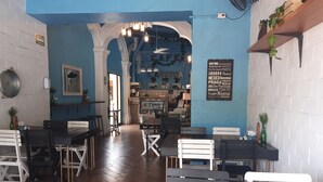 A restaurant interior with wooden tables and chairs, a blue wall, and a sign listing various cities. - Hotel La Casona de Don Jorge (Colima)