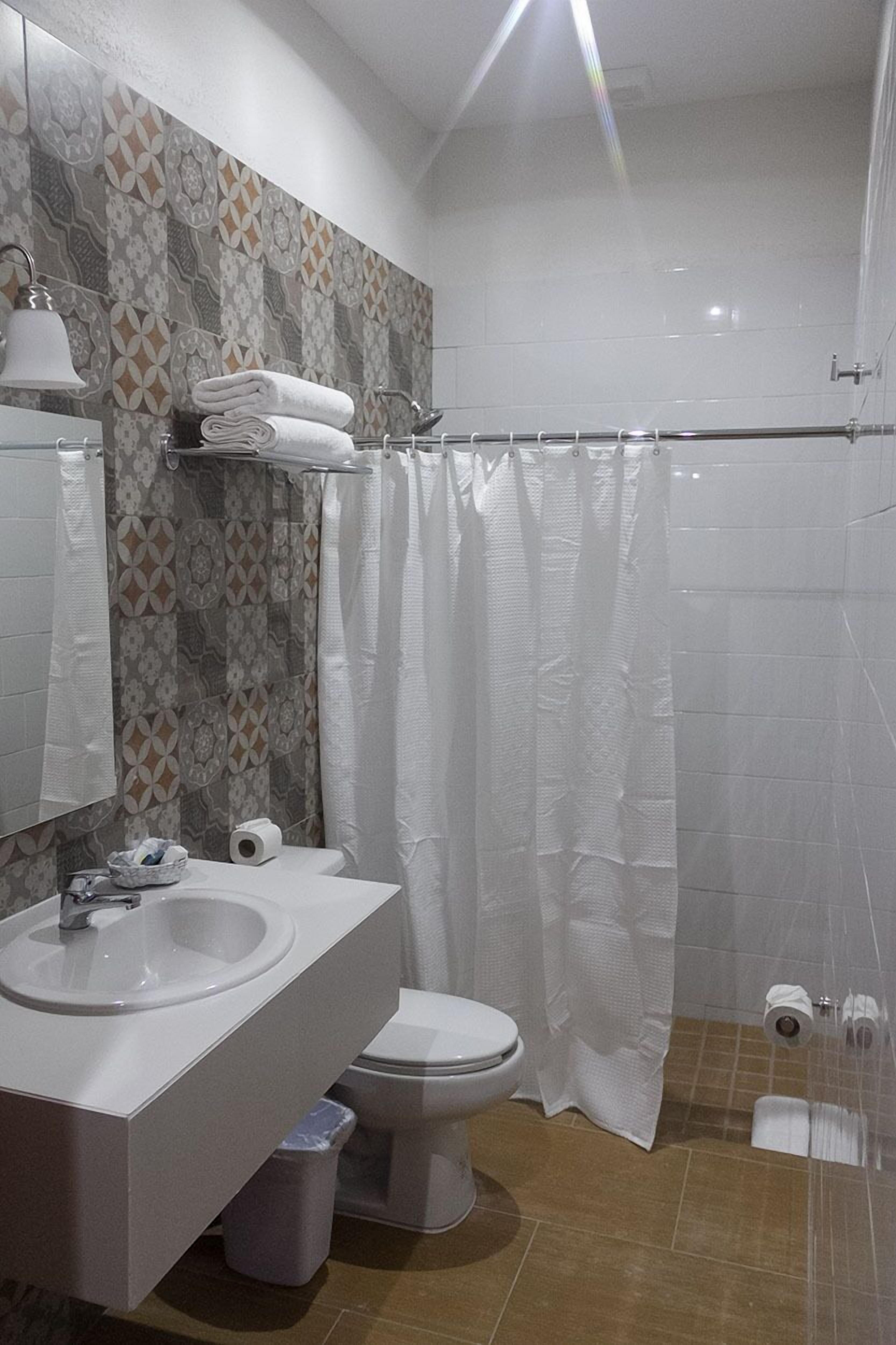 Un baño con lavamanos, inodoro y cortina de ducha.