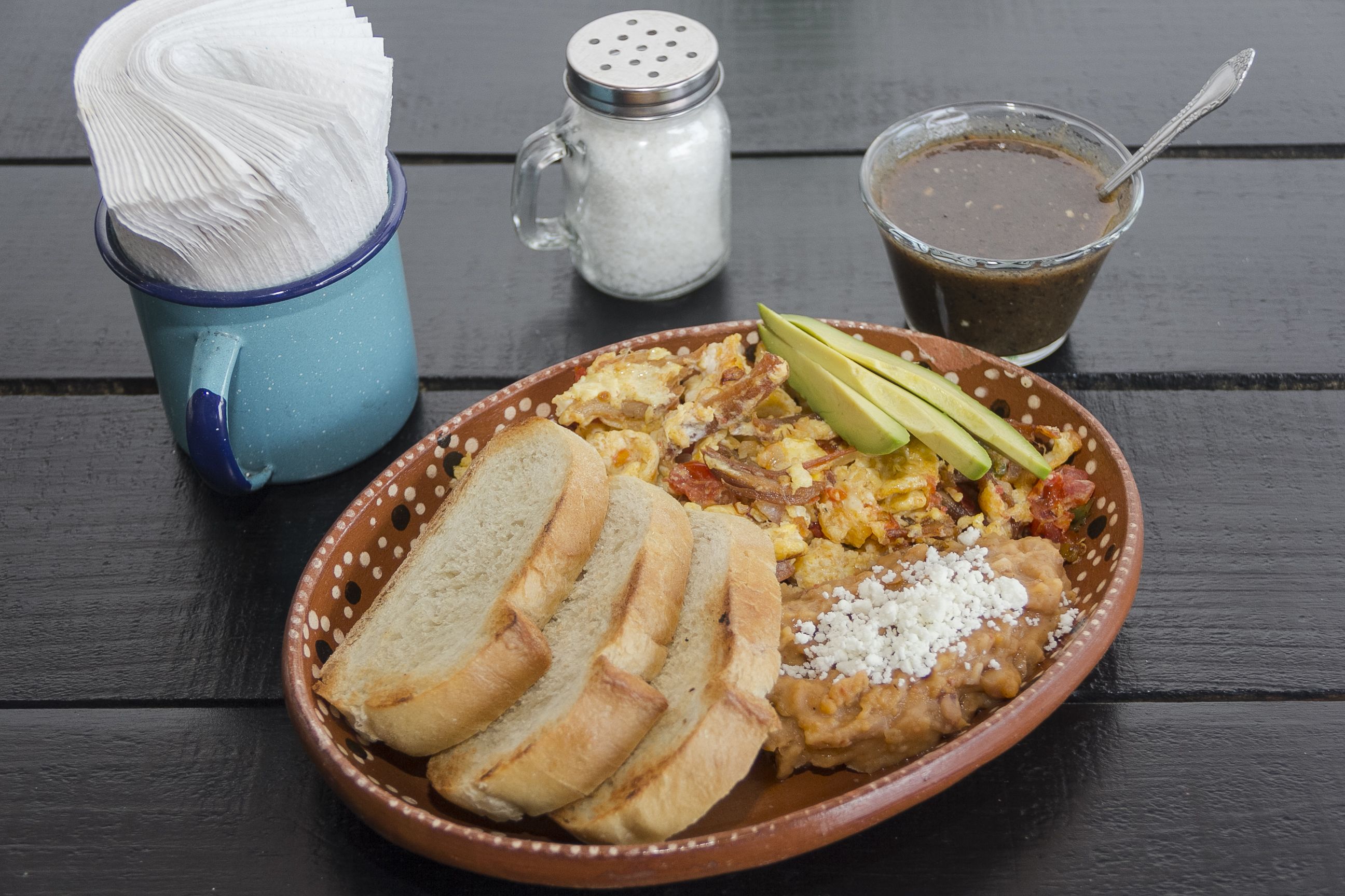 A meal with bread, avocado, and a drink on a table.