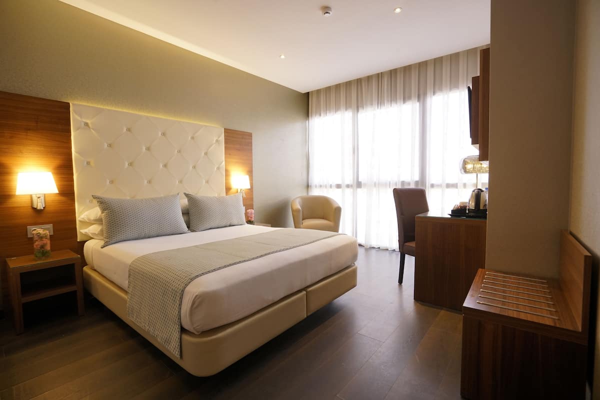 A modern hotel room with a large bed, a desk, and a chair.