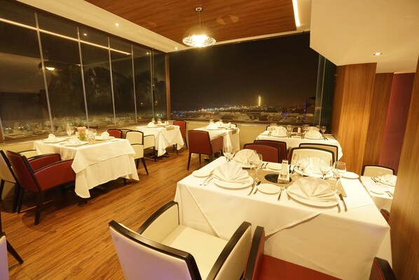 A restaurant with tables set for dining, large windows offering a city view, and a modern interior design. - AZ Hôtels Kouba (Algiers)