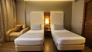 Una habitación de hotel con dos camas, un sofá, una mesita de noche y una lámpara.