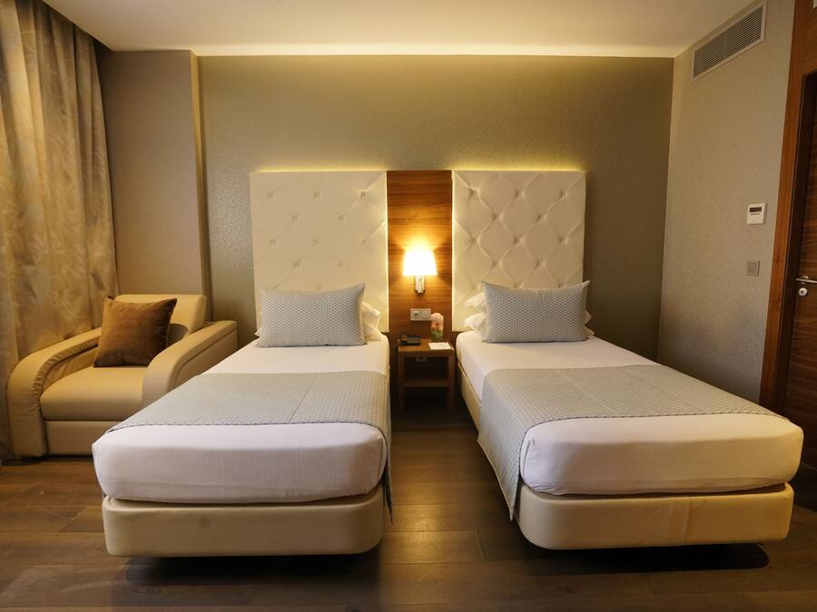 Una habitación de hotel con dos camas, un sofá, una mesita de noche y una lámpara.