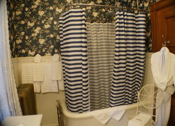 A bathroom with a bathtub, a shower curtain, and a white towel rack.