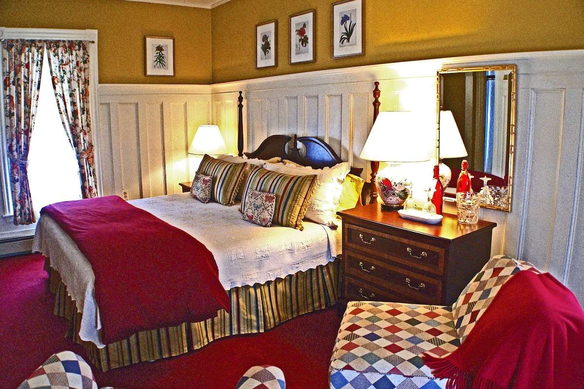 A well-appointed bedroom with a large bed, two bedside tables, a dresser, and a mirror.