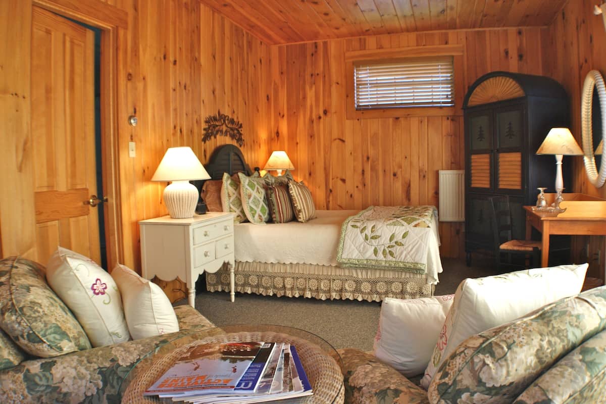 A cozy room with a bed, two nightstands with lamps, a dresser, and a chair.