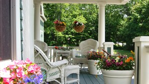 A porch with wicker furniture and potted flowers.