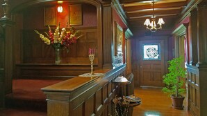 A grand hallway with a wooden floor, a chandelier, a vase of flowers, and a potted plant.