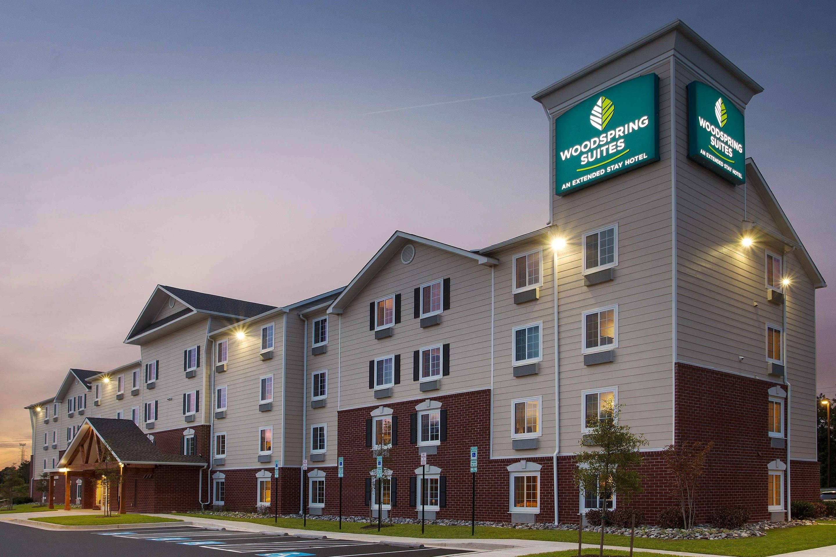 A multi-story hotel with a prominent signage for 'Woodspring Suites' indicating it is an extended stay hotel.