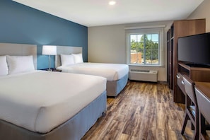 Habitación de hotel con dos camas, televisión y ventana con persianas.