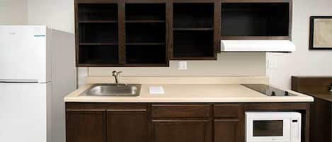 A kitchen with dark wooden cabinets, a white refrigerator, a sink, and a built-in microwave.