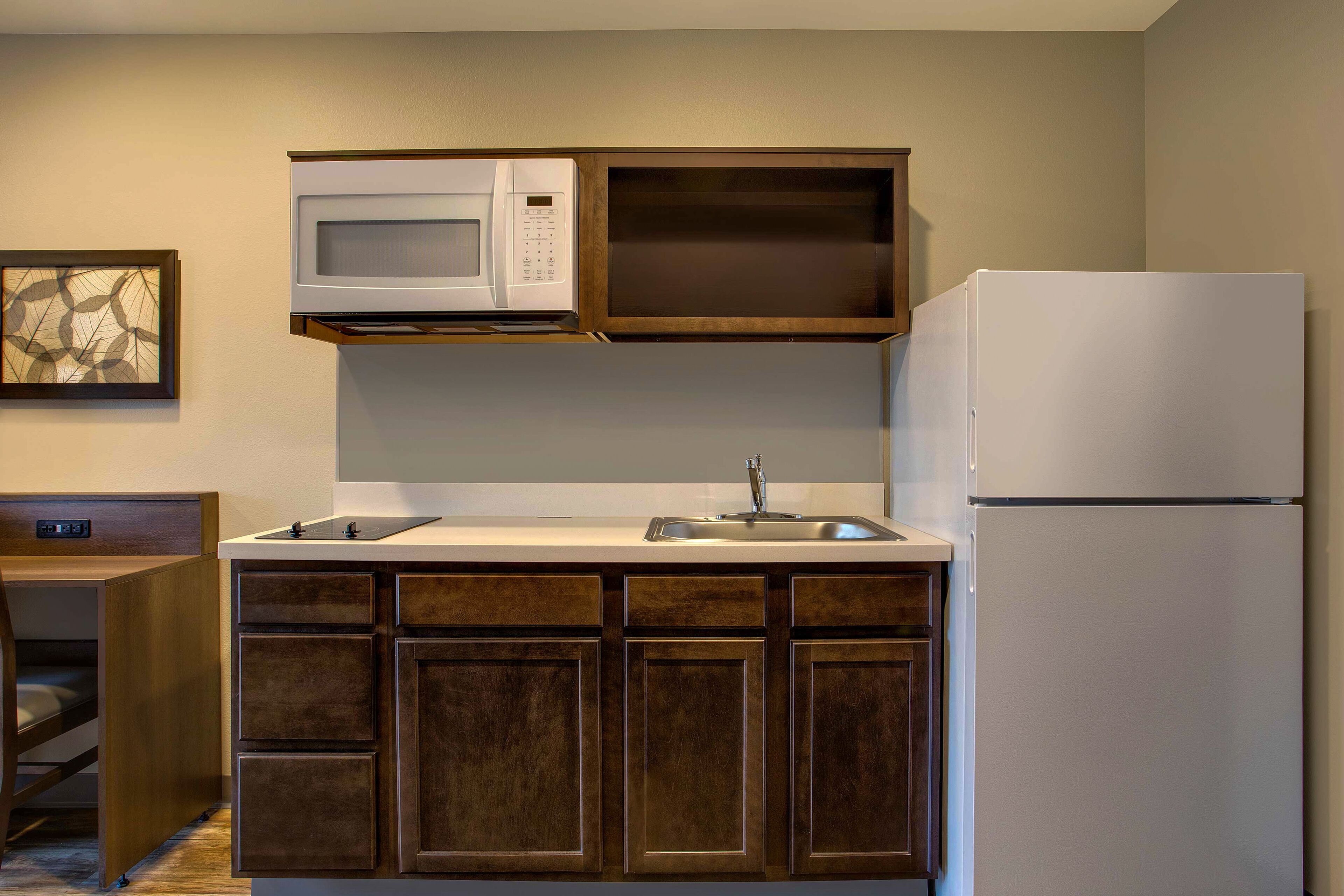 Una cocina compacta con microondas, lavamanos y refrigerador.