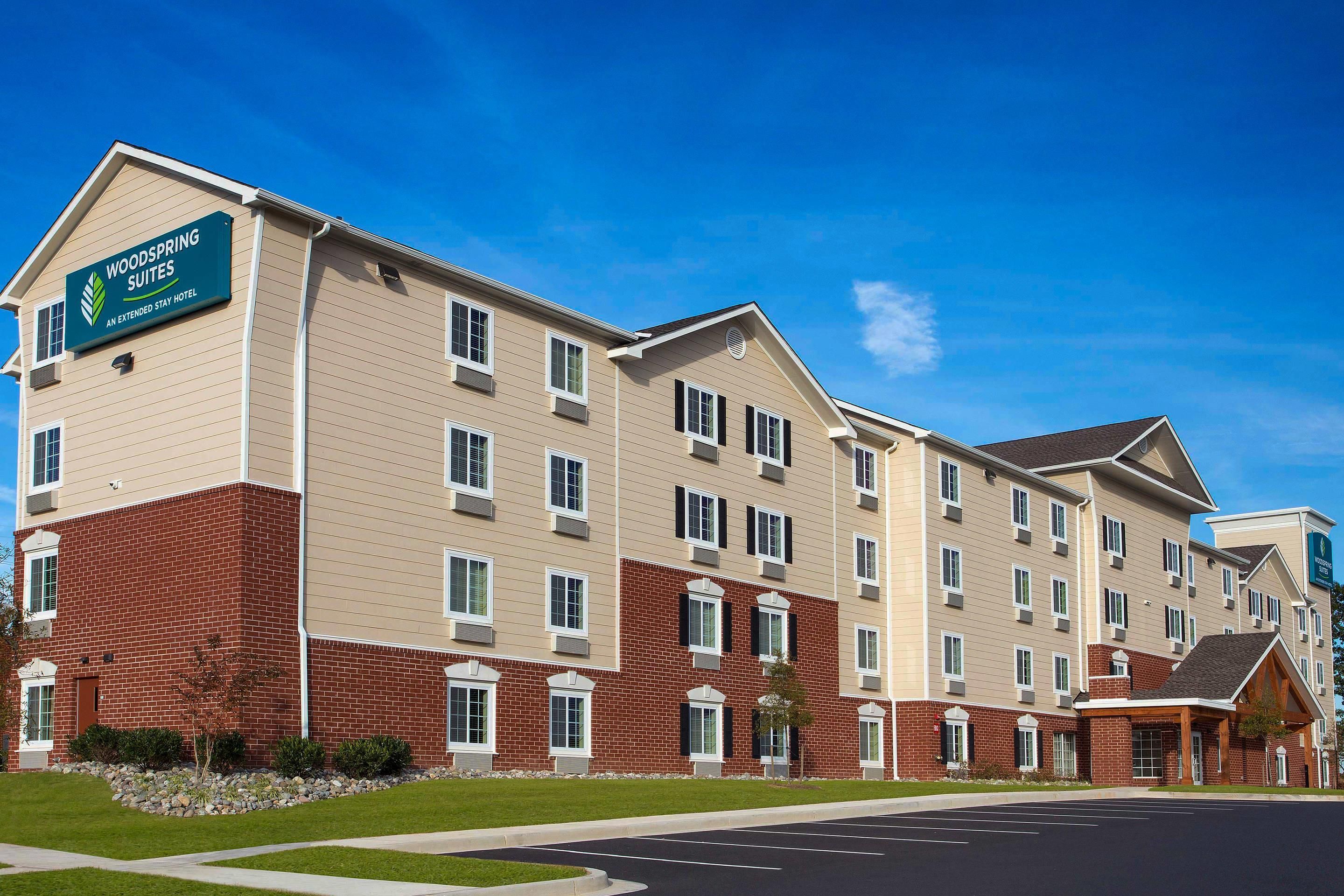 Un hotel de varios pisos con fachada de ladrillo y un letrero que indica que es un Woodspring Suites Extended Stay Hotel.