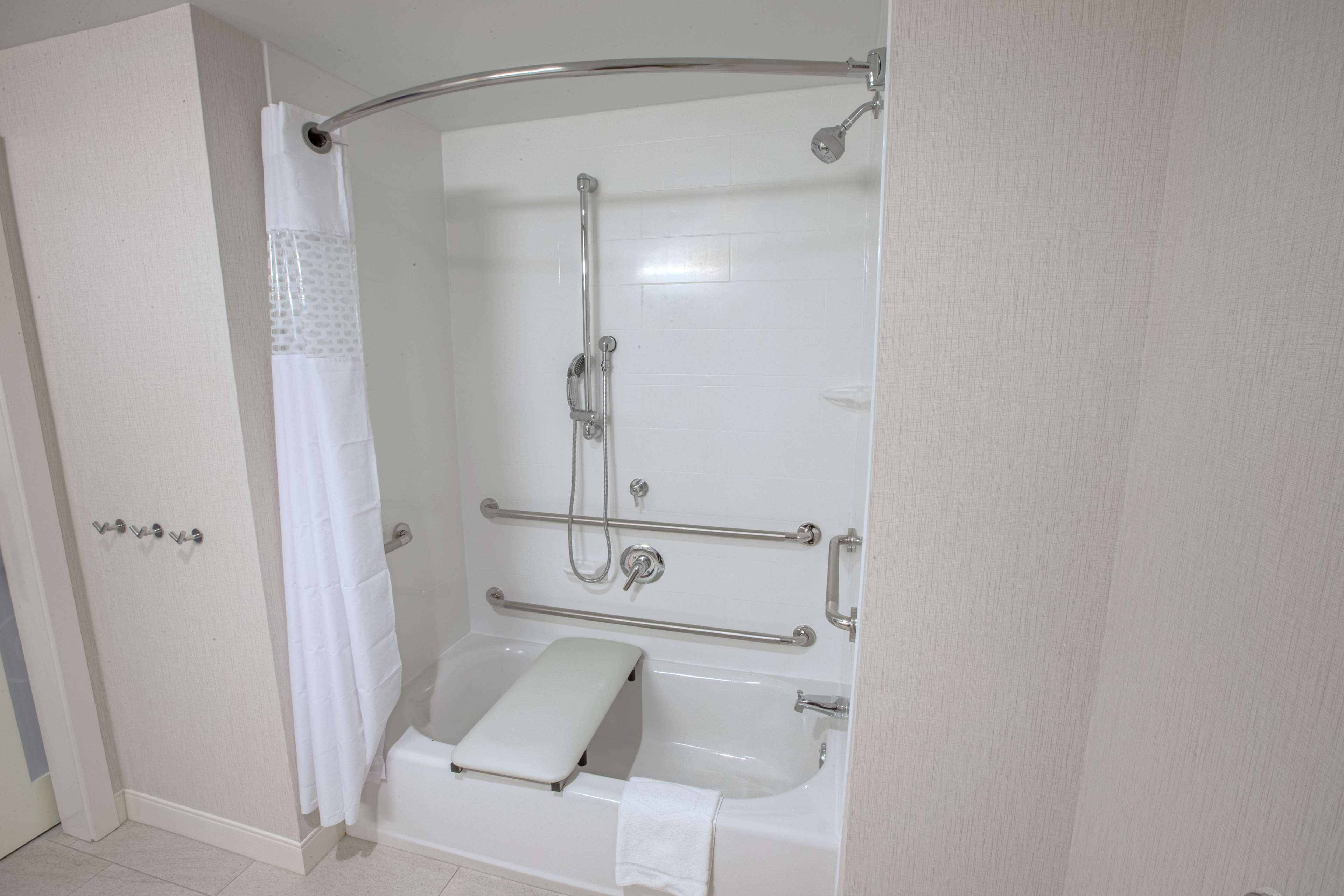 A modern bathroom with a walk-in shower, grab bars, and a white bathtub.