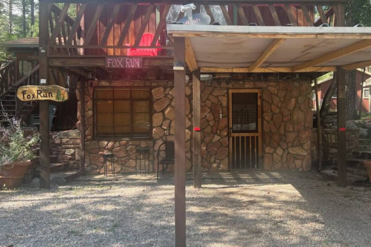 A rustic cabin with a stone exterior, a covered patio, and a sign reading "Fox Run".