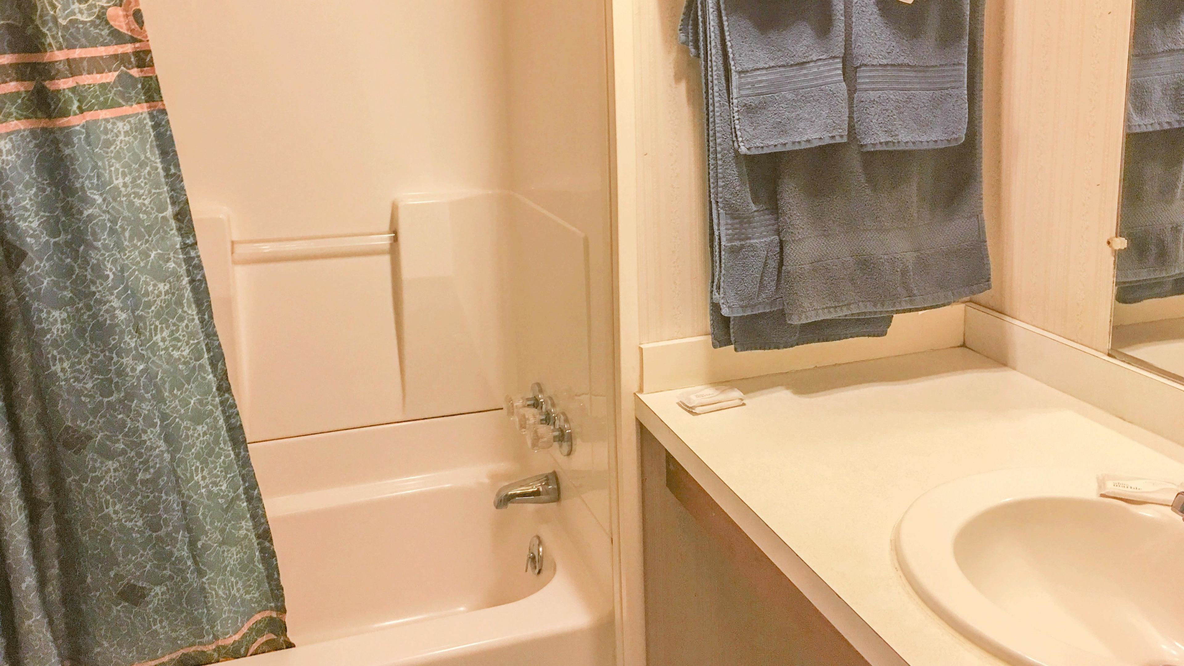 A bathroom with a bathtub, a sink, and a mirror.