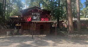 A rustic cabin with a stone foundation, a wooden deck, and a sign indicating it is a 'Fox Run' establishment. - Canyon Cabins (Ruidoso)