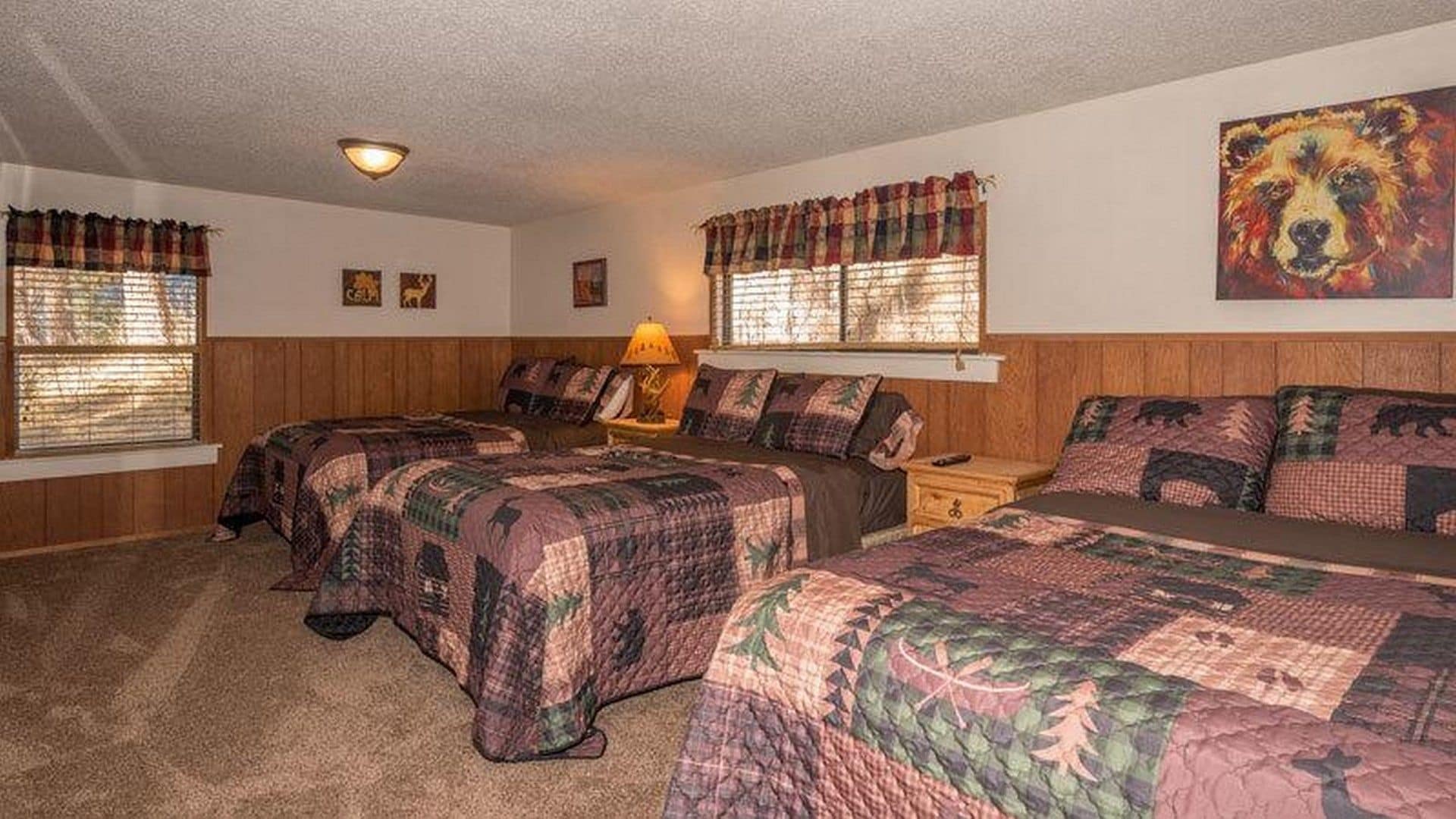 A room with two beds, a nightstand, a lamp, and a painting on the wall.