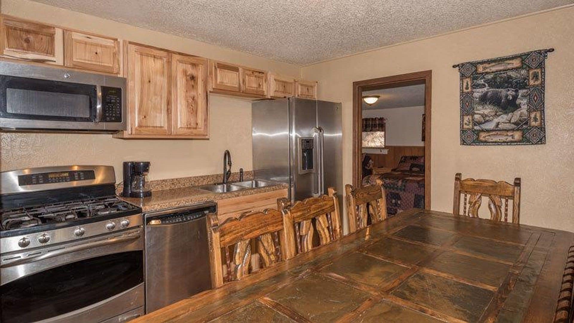 A kitchen with wooden cabinets, stainless steel appliances, a tiled backsplash, and a dining area with a large table and chairs.