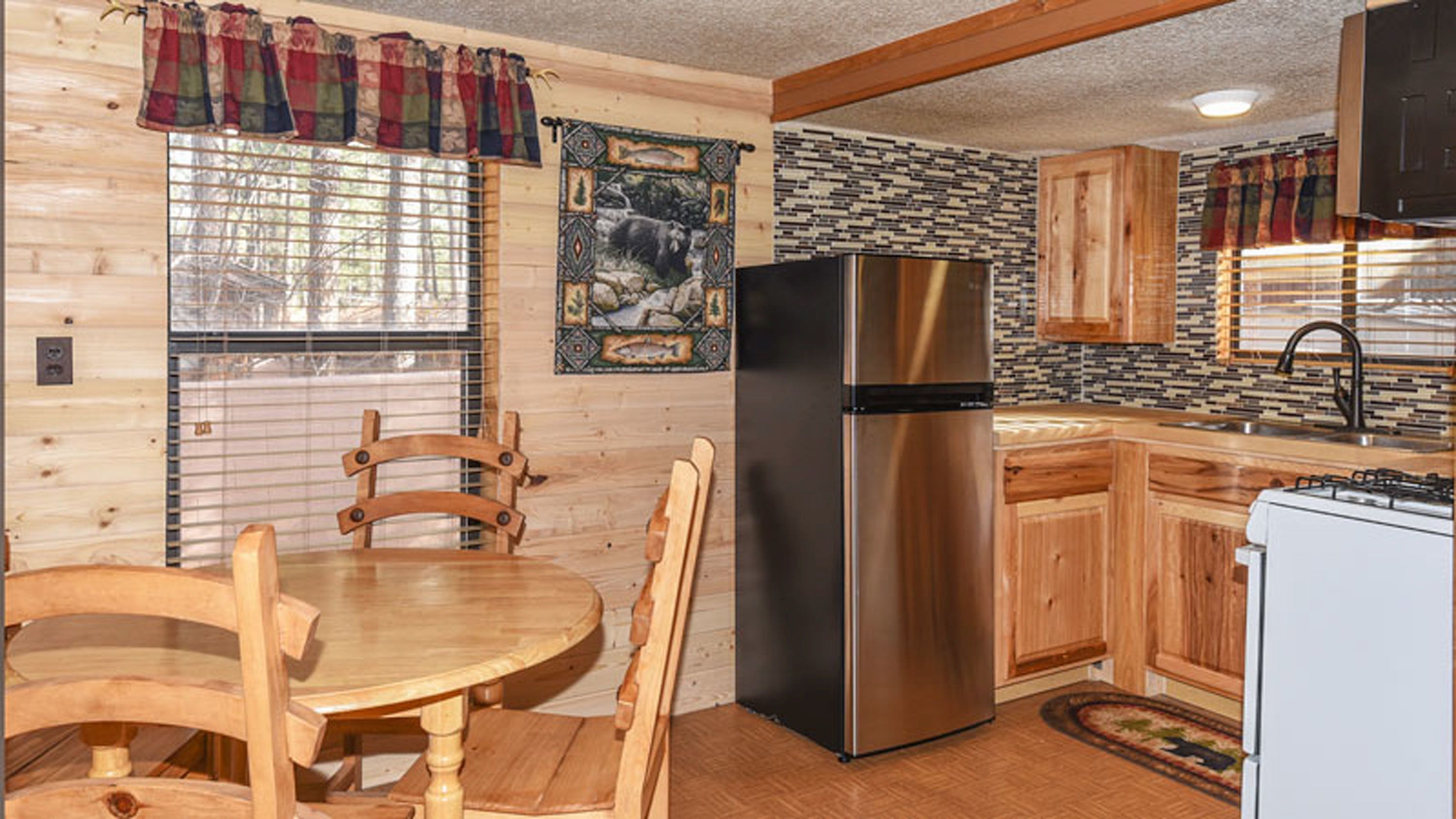 A compact kitchen with wooden cabinets, a stainless steel refrigerator, and a small stove.