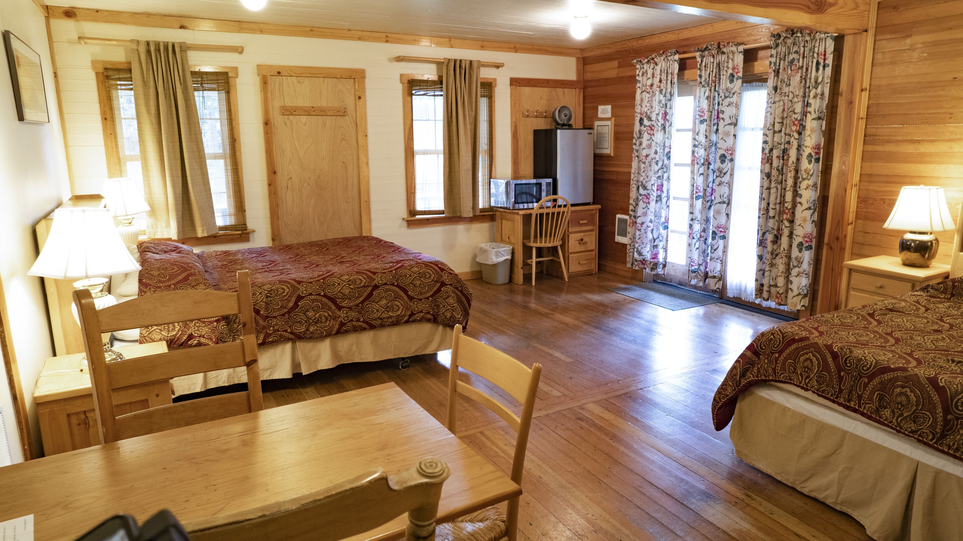 A cozy room with two beds, a desk, a chair, and a television.