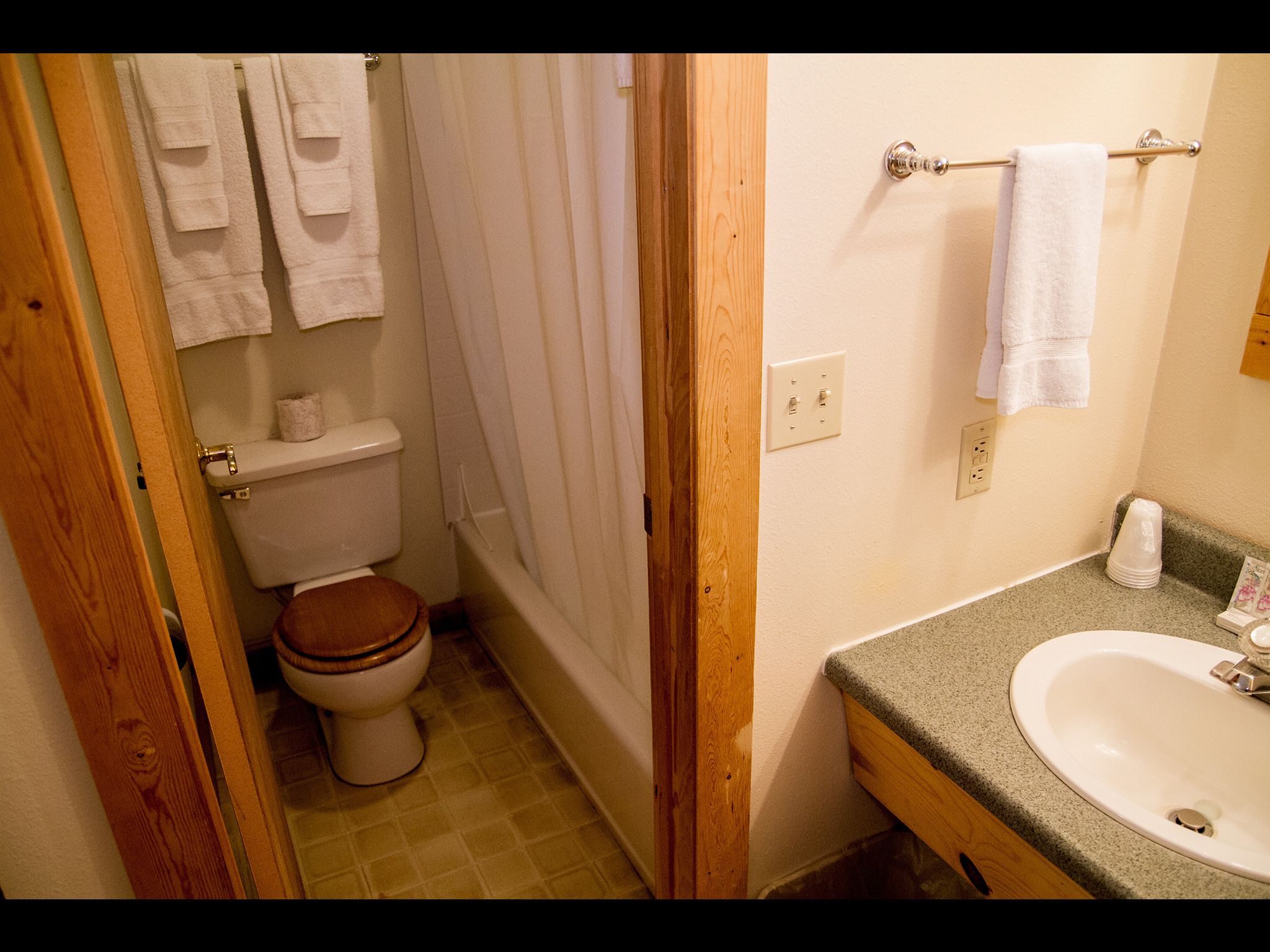 Un baño con inodoro, cortina de ducha, lavabo y toallero.