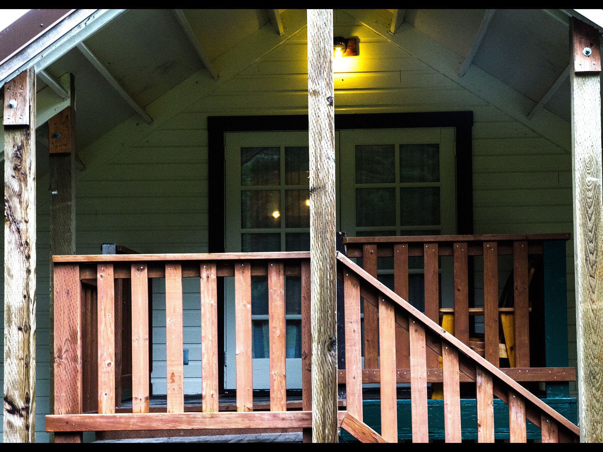 A wooden porch with a wooden railing and a staircase leading up to a door.