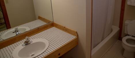 Un baño con tocador de madera, dos lavamanos, un espejo y una bañera.
