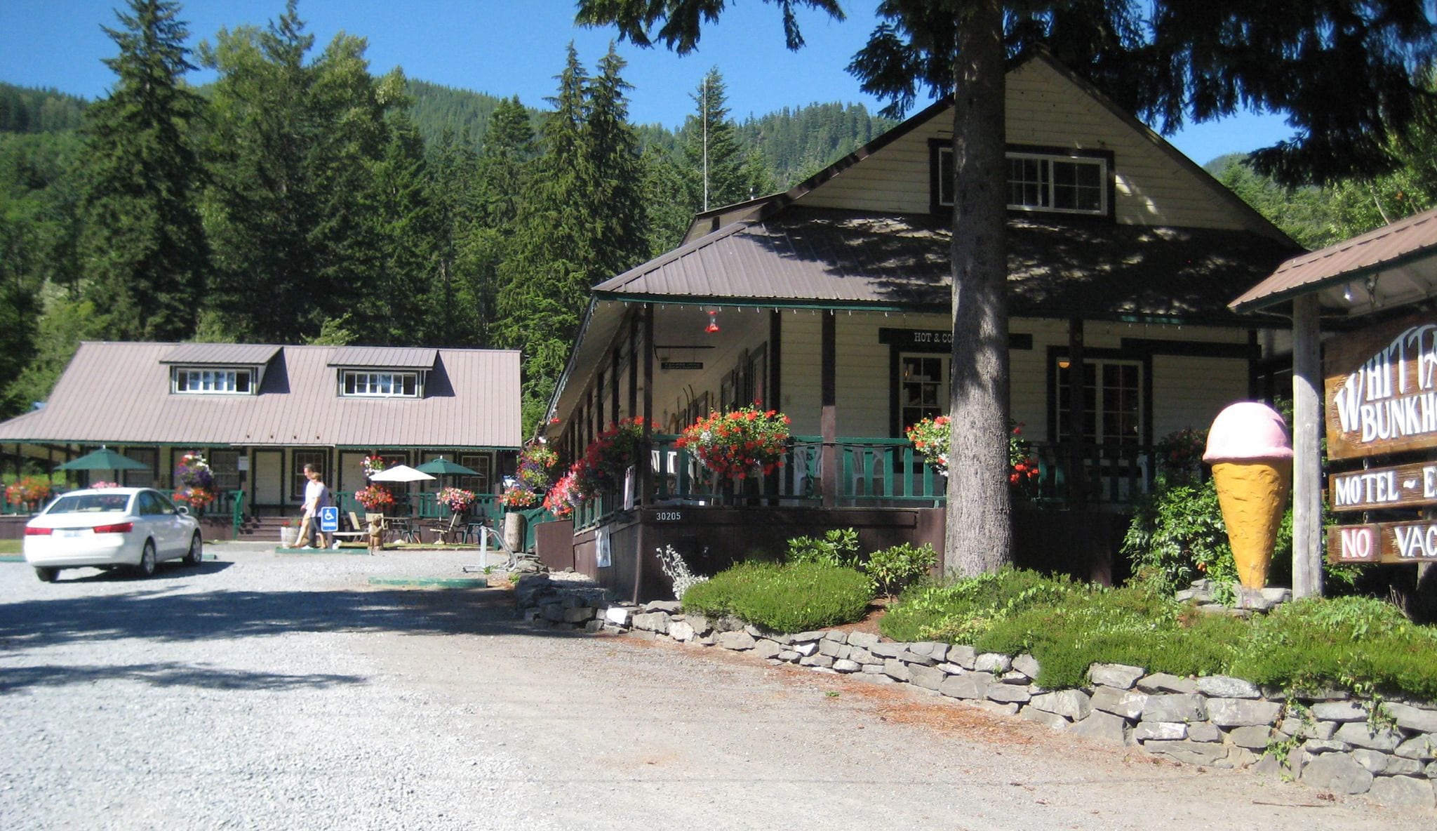 A two-story building with a porch, stone wall, and flower boxes.