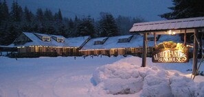 Ein mit Schnee bedecktes Gebäude mit einem Schild, auf dem 'Whittaker's Bunkhouse' steht, bei Nacht.