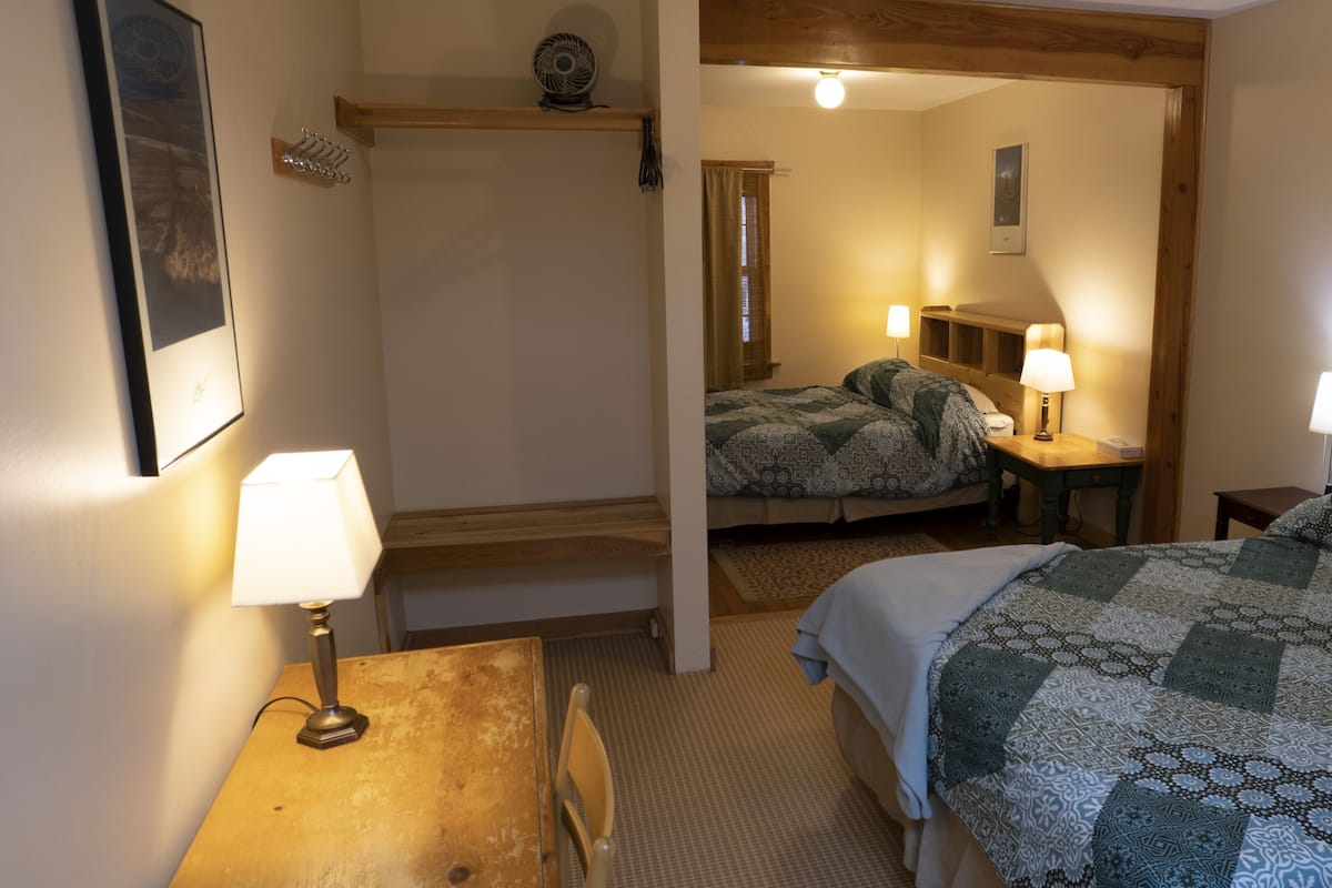 Ein Schlafzimmer mit Bett, Schreibtisch, Stuhl, Lampe und Spiegel.