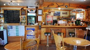 L’intérieur d’un restaurant est aménagé avec des meubles en bois, un coin bar et un menu écrit à la craie sur un tableau noir.