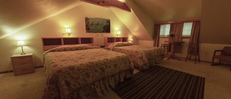 A room with two beds, a desk, a chair, and a window with curtains.