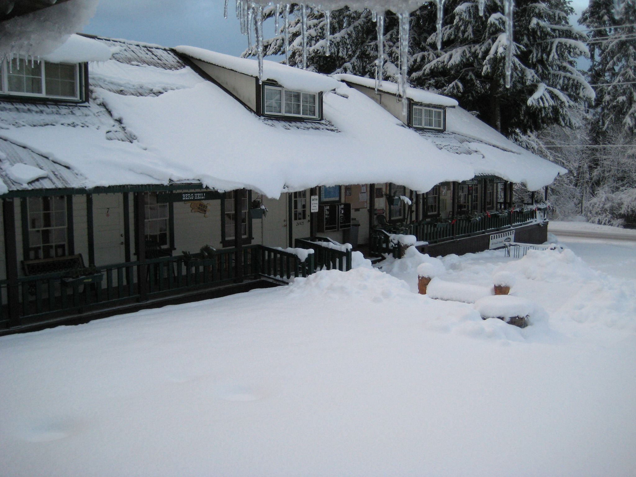 Une rangée de bâtiments recouverts de neige, avec une clôture en bois devant.