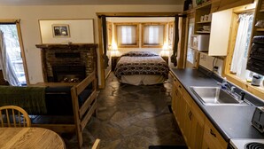 Une cuisine de taille réduite avec un sol en pierre, des placards en bois, une cuisinière encastrée et un évier.