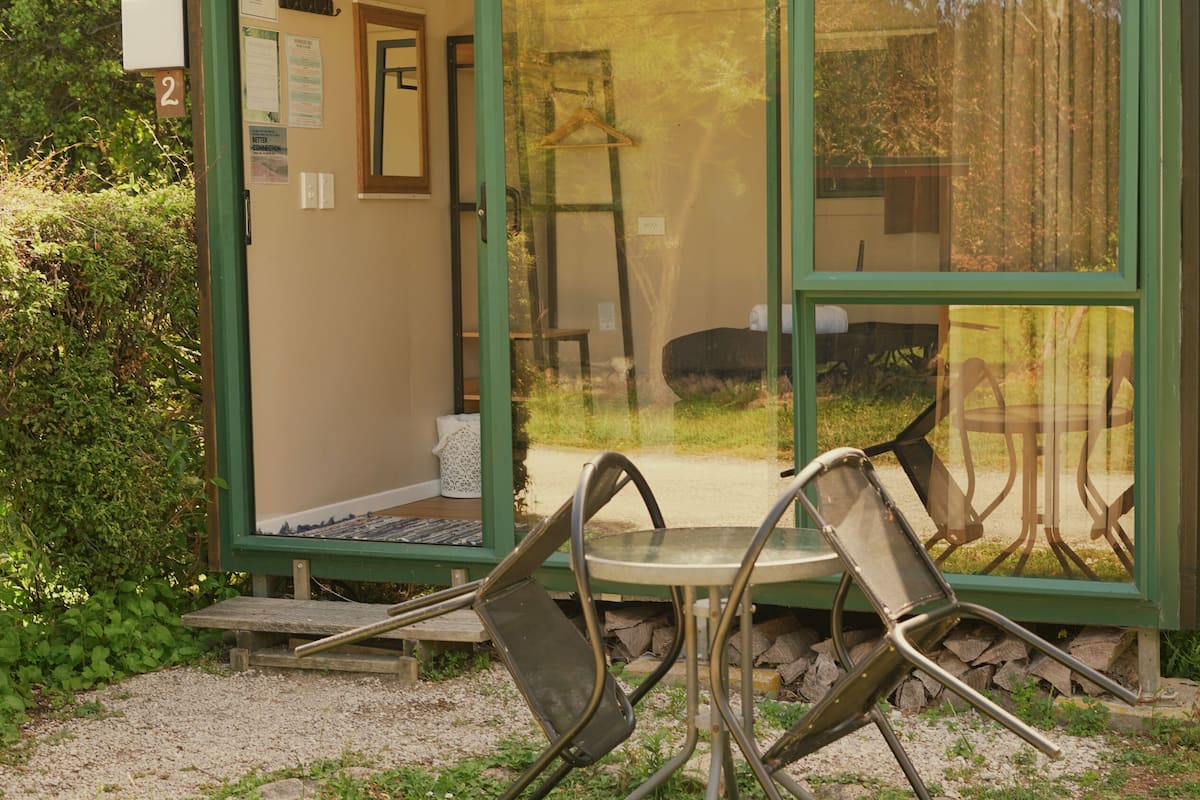 A glass-walled room with a wooden bench and chairs outside.