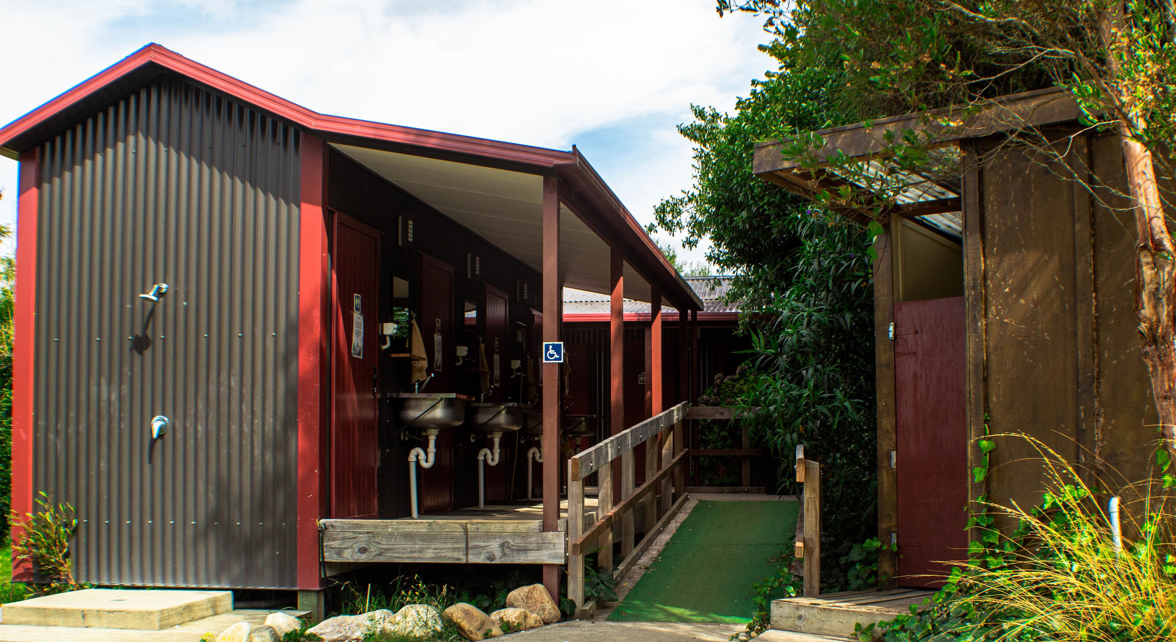 A rustic building with a covered porch, a wheelchair-accessible entrance, and a small outdoor area with a green mat.