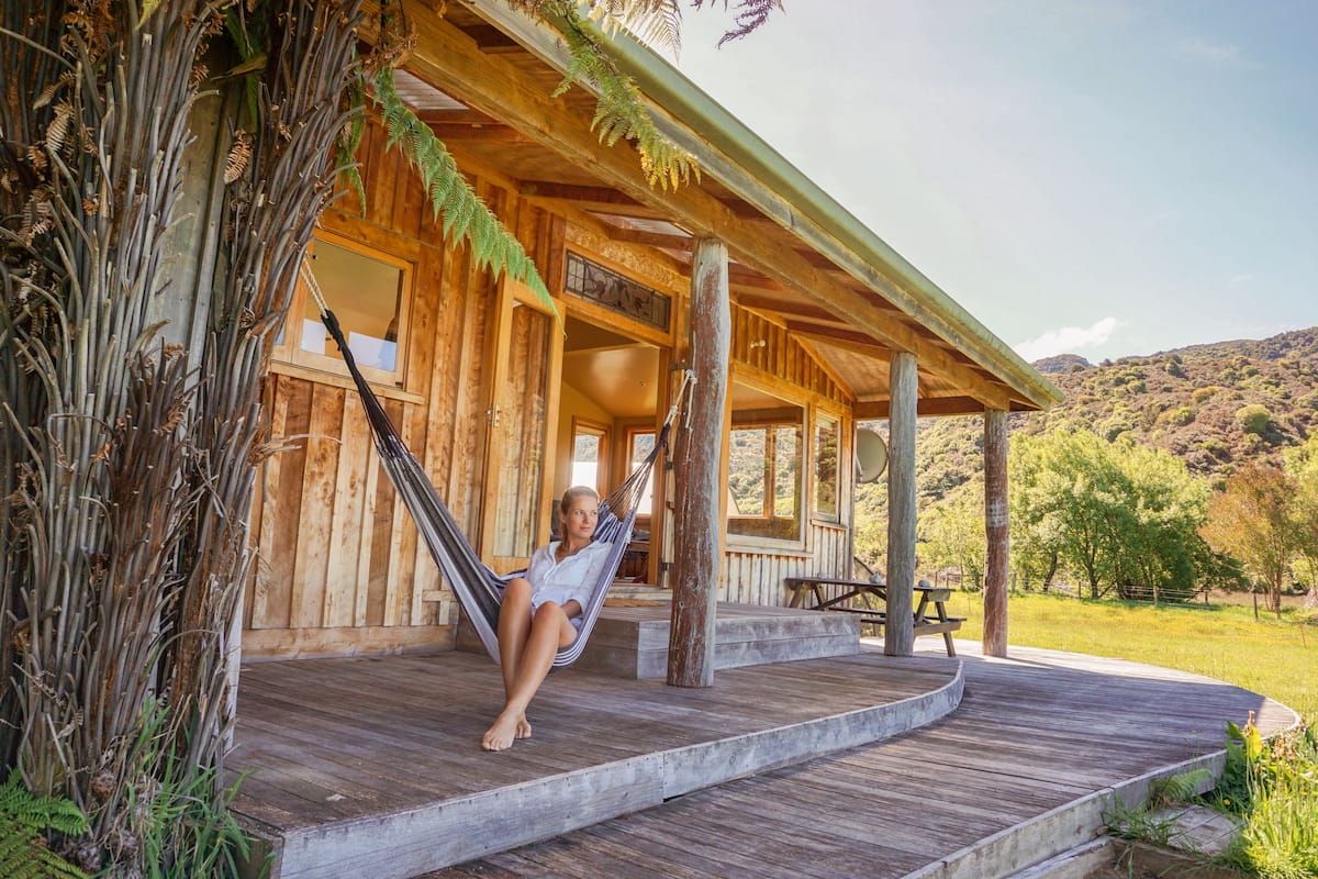 A wooden cabin with a porch, a hammock, and a picnic table.